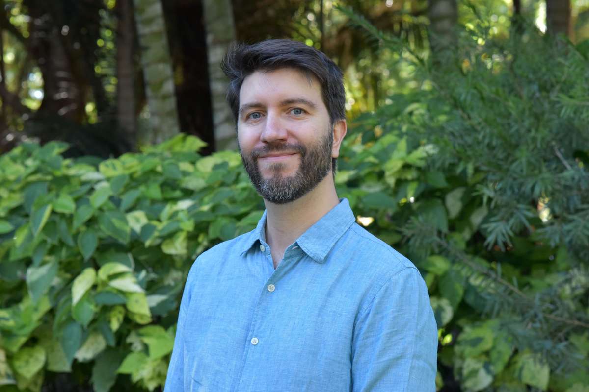 Dr Jeremy De Valck stands outdoors, in front of greenery.jpg