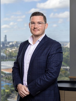 Profile image of Jesse Trecco Alexander in an office setting, wearing a navy suit coat and white business shirt