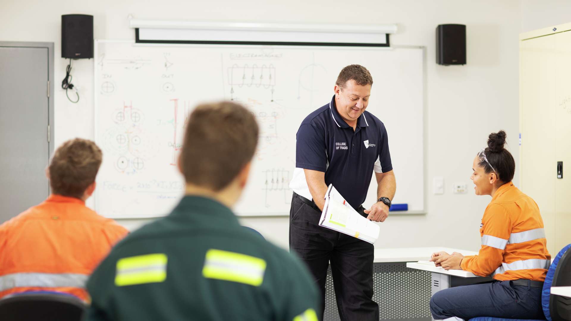 CQU TAFE teacher shows a student study materials in the classroom.