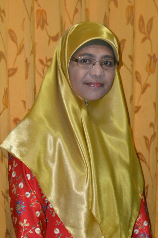 Lily Ishak smiling with reading glasses whilst wearing a gold hijab and red coat