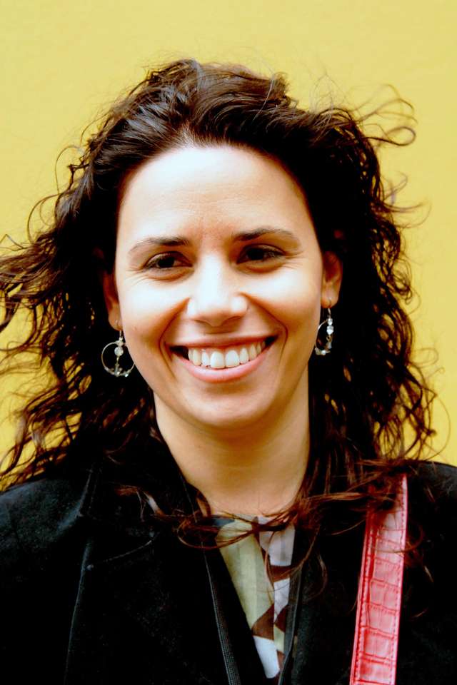 Tanya Orman smiling with wavy hair and yellow background