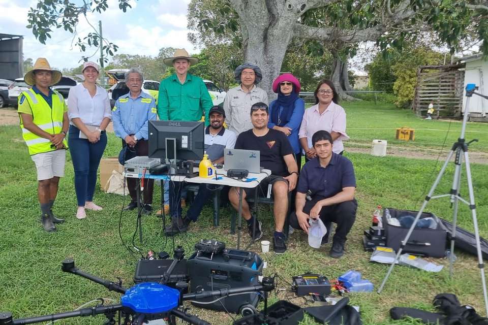 CQUniversity and Foxwell Farms represenatives at a farm, in front of a desk with computer and drone equipment..