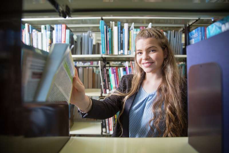 A Mackay scholarship student picking a book in a library