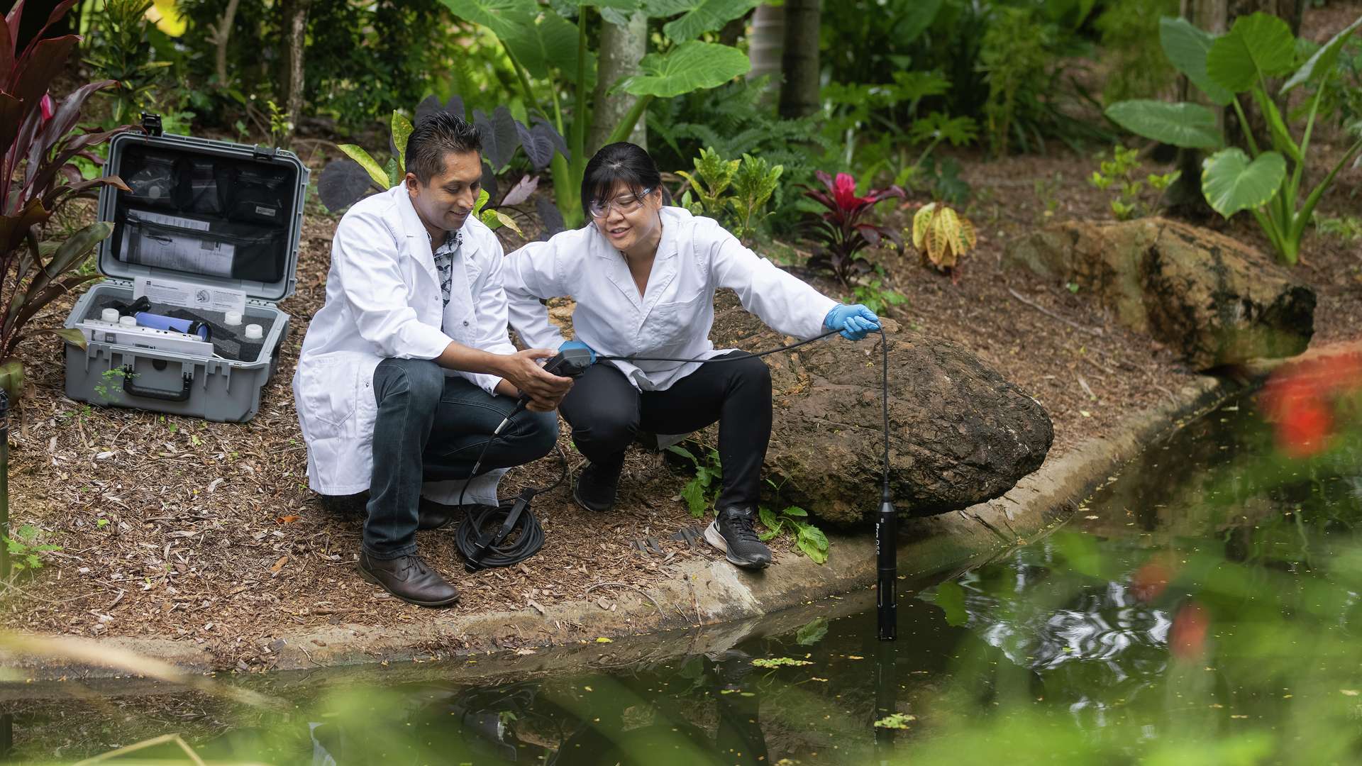 Two agriculture research students collecting data from a pond