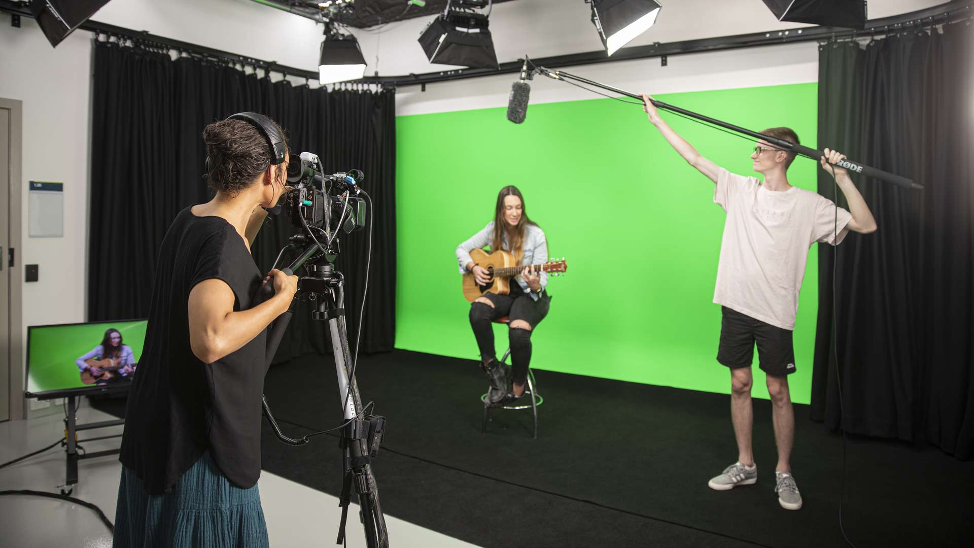 Digital Media students filming a guitarist in front of a green screen.