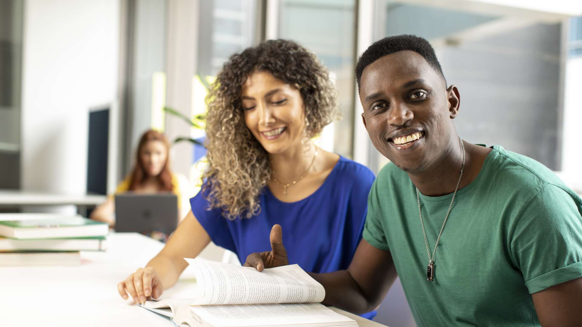 Two students sharing, reading a book