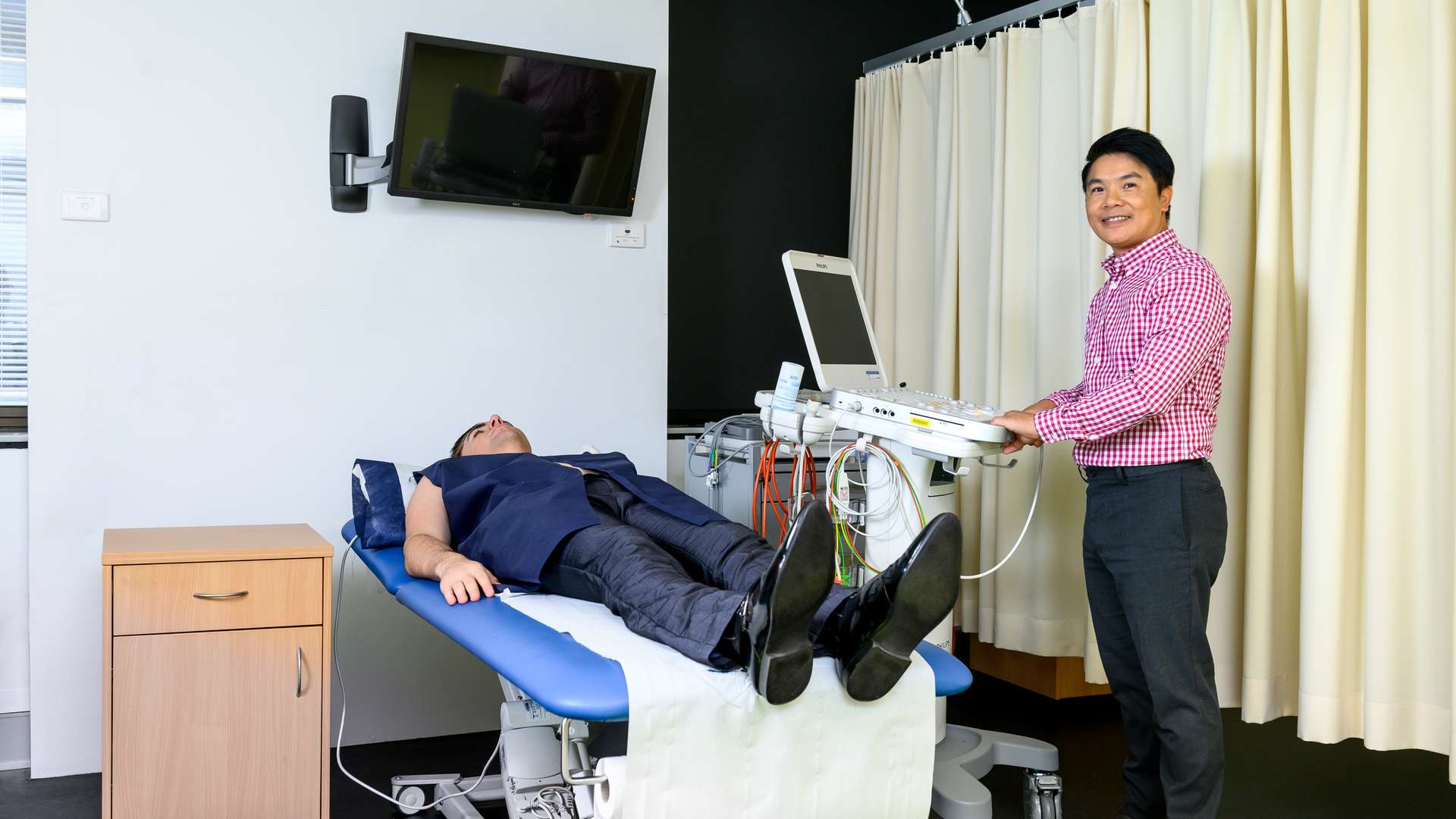 A student using an Echocardiography medical machine on a patient