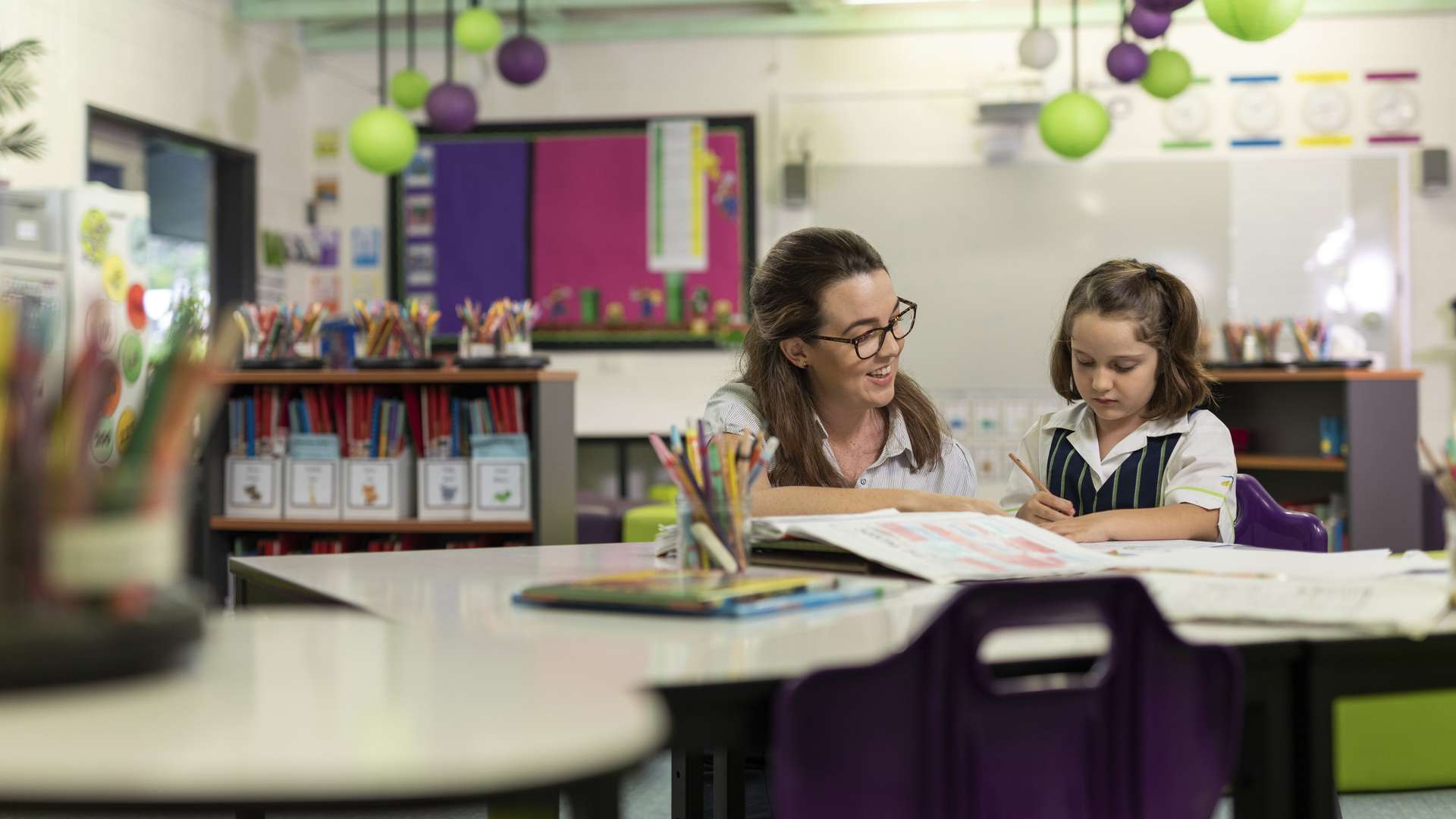 A teaching student helping a child with their writing.