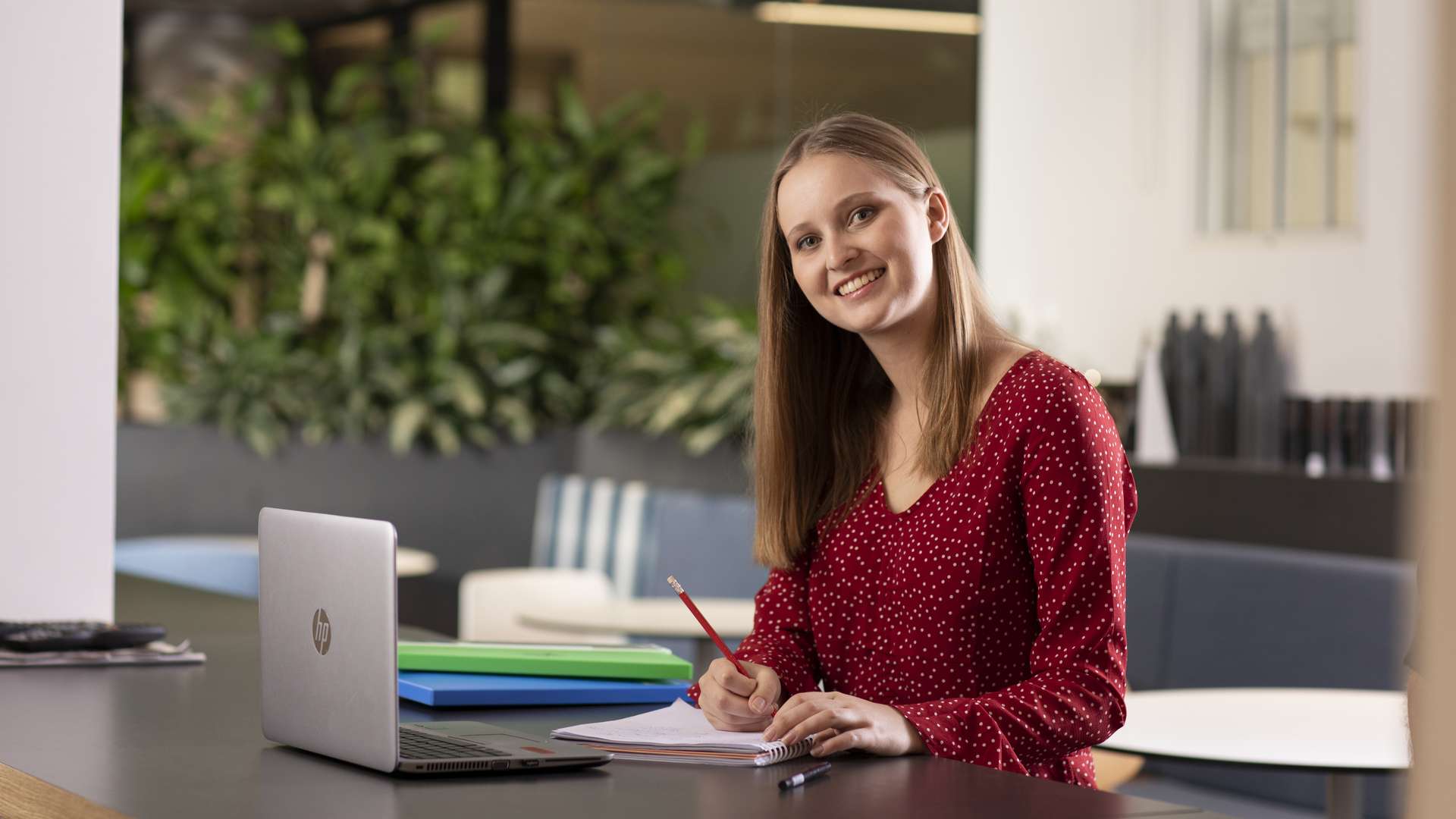 Student studying at a table in a public, campus study space