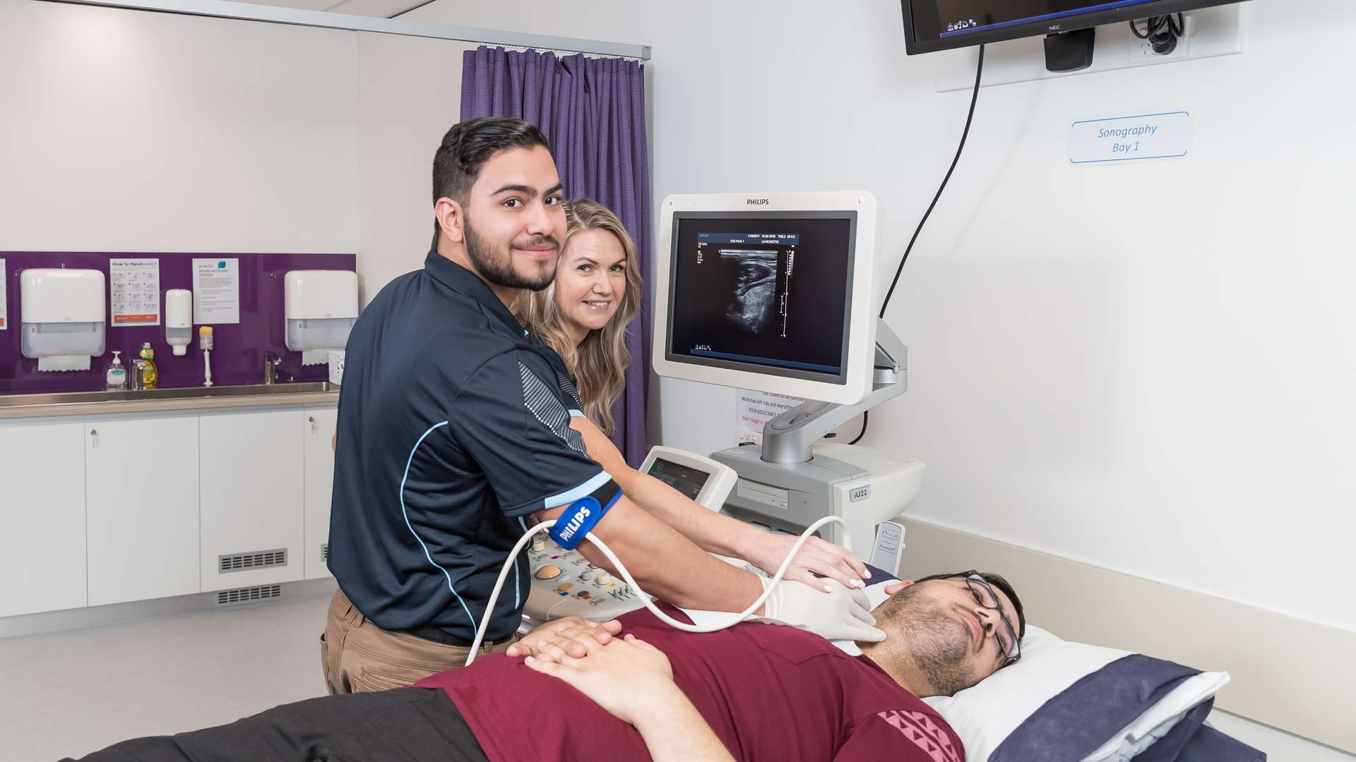 Students using a Sonography machine on a patient's neck