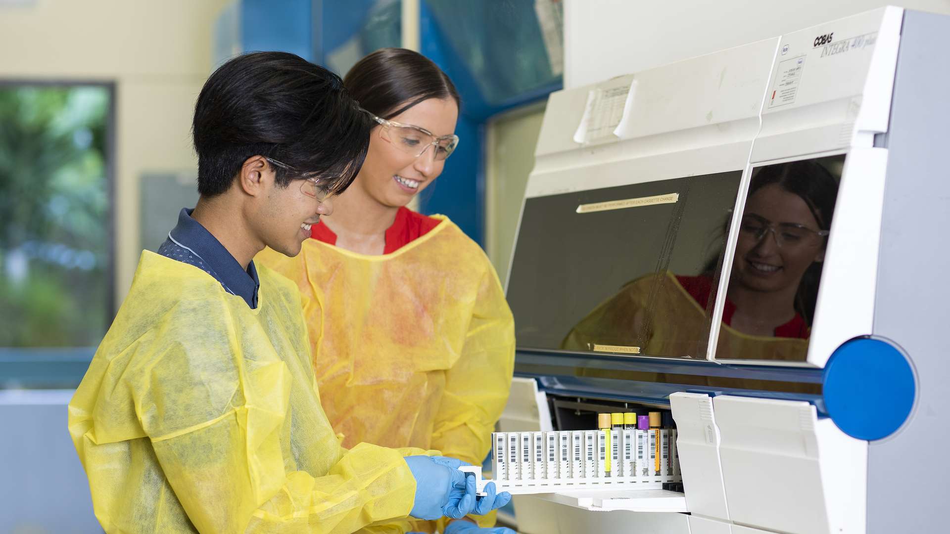 Two medical science students working in a lab on a large medical machine.