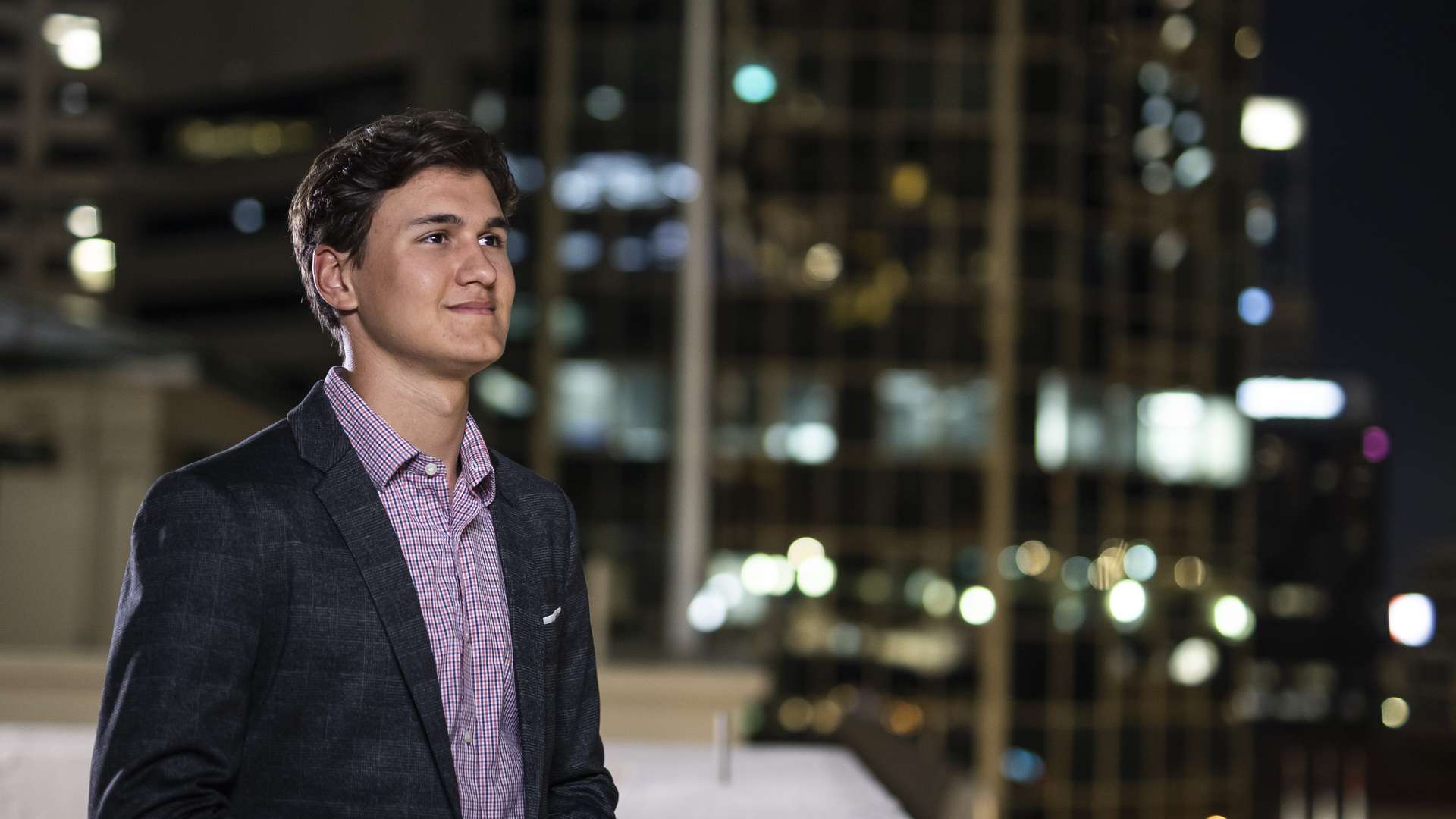 Man standing on a roof balcony in a city, at night