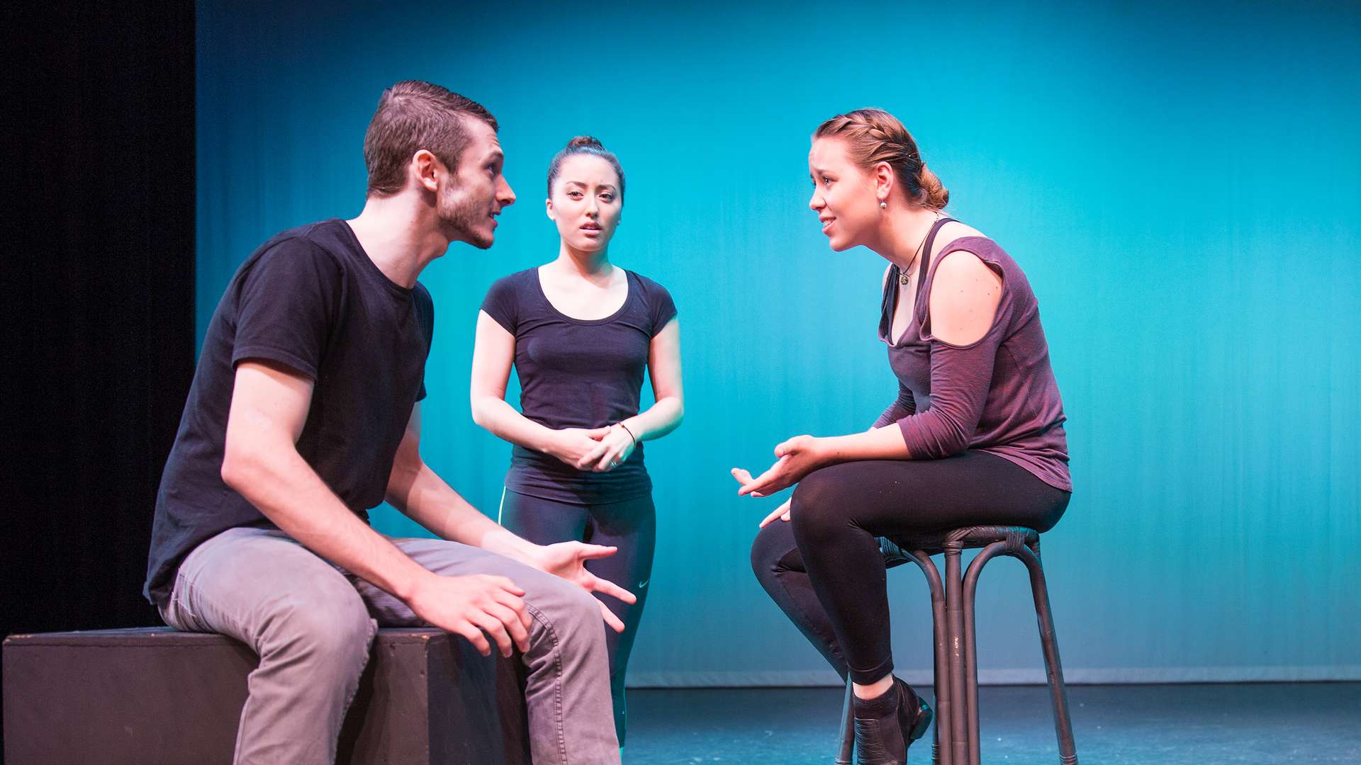 A close up of three students acting on a stage.