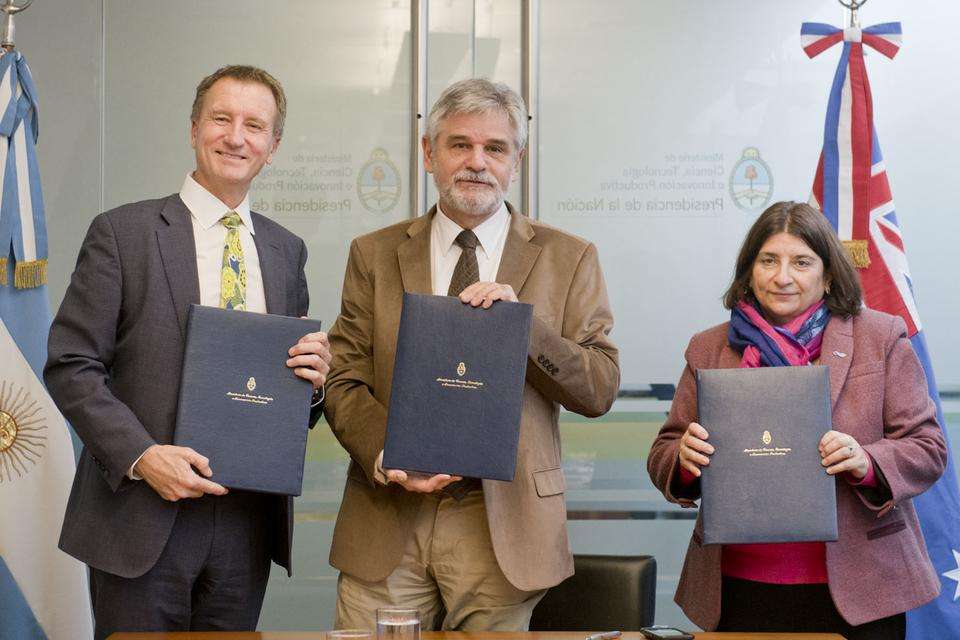 Professor Nick Klomp,Argentina’s Minister for Science and Technology Daniel Filmus and CONICET President Dr Ana Franchi stand together following the signing of an MOU between CQU, MINCYT and CONICET. The three stand alongside a timber boardroom table with the Argentine and Australian flags in the background.