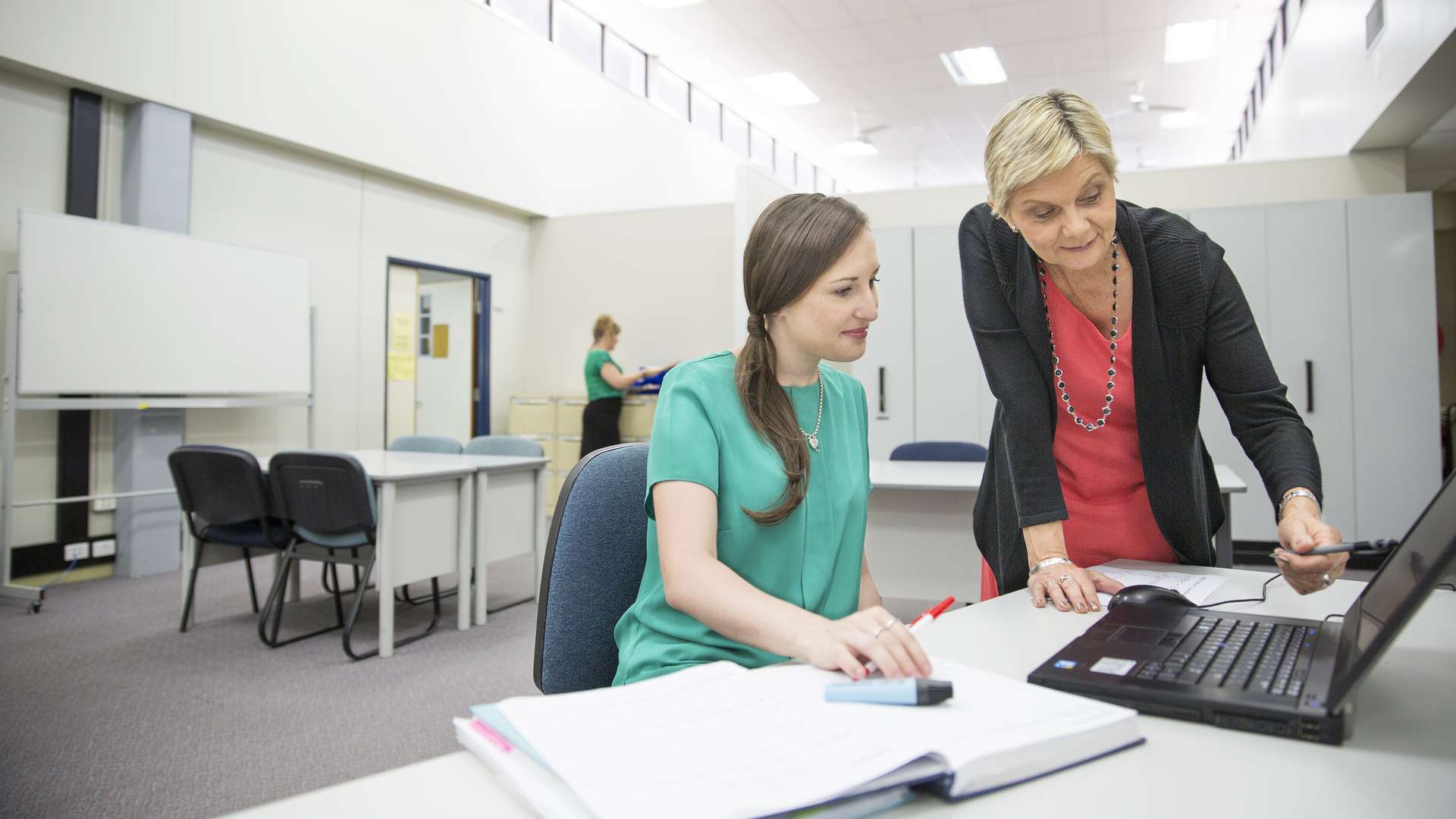 Student, in a classroom using a computer receiving help from the teacher