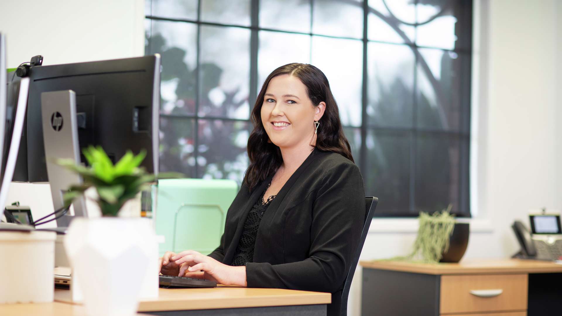 Lady sitting working at office desk on desktop computer