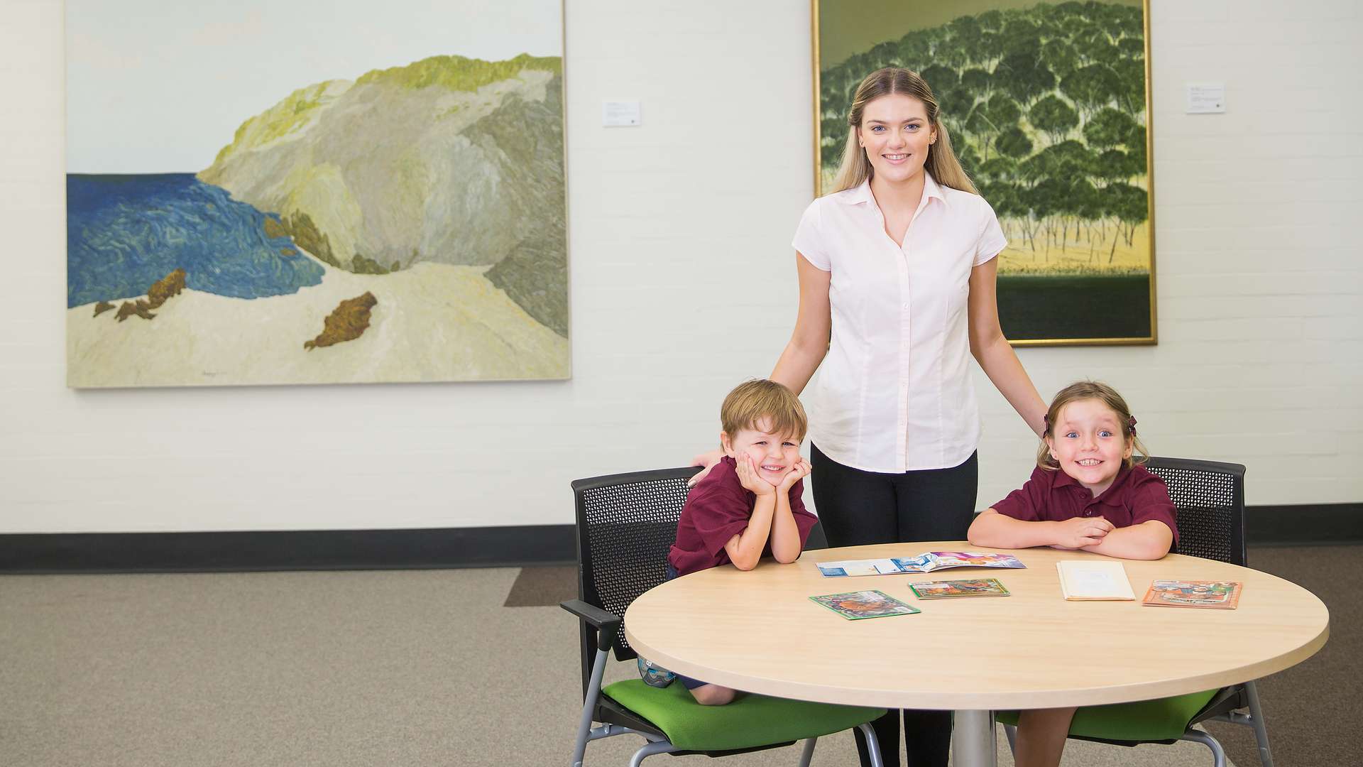 A teaching student helping two children read.