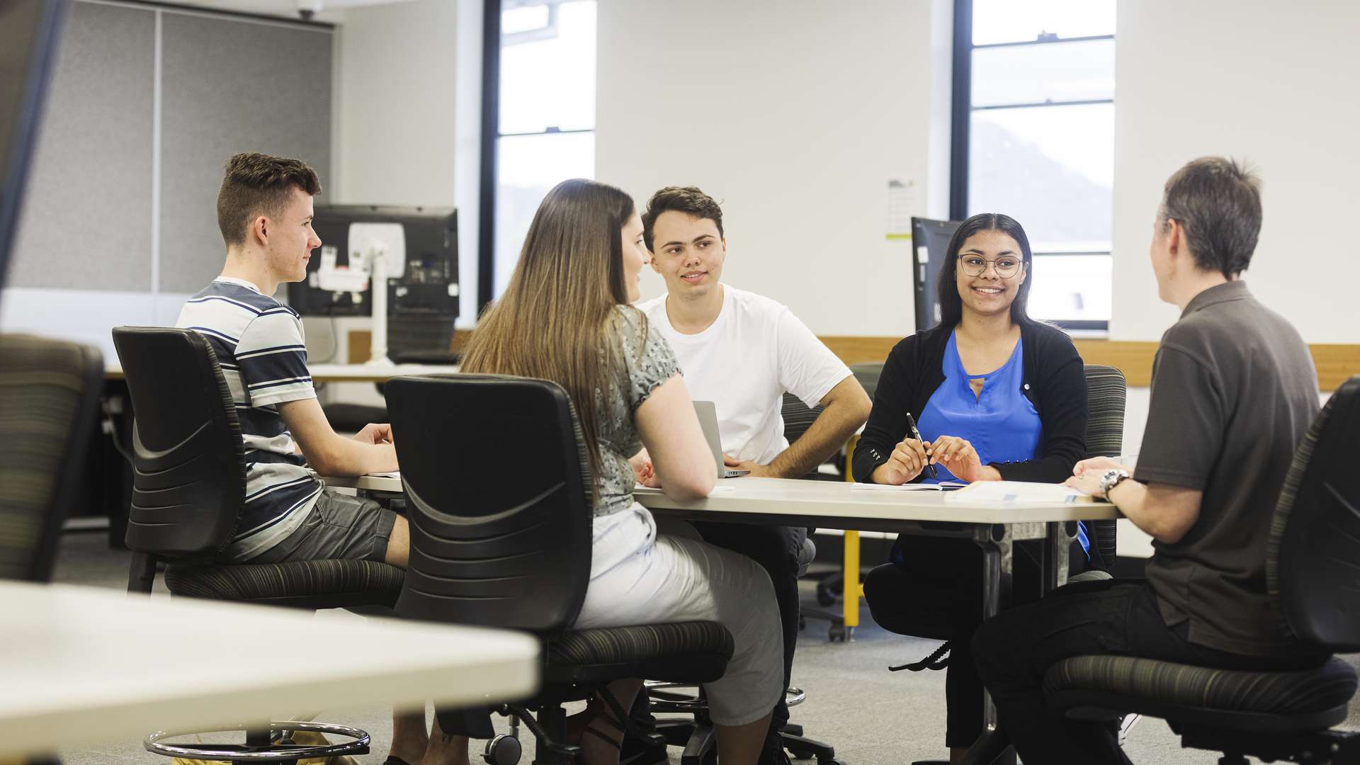 Five students sitting down having a discussion.