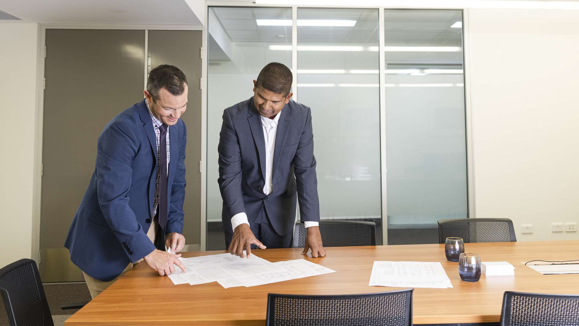 Two construction managers overlooking and discussing documents.