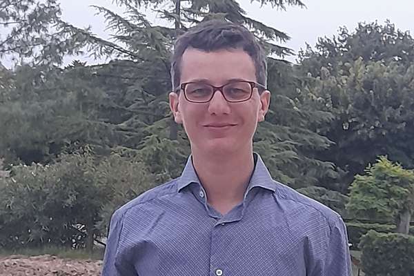 Demis Corvatta smiling with some threes on his background