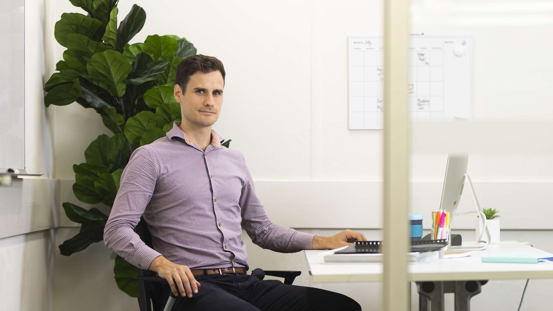 Man sitting at a desk, seen through open door and window