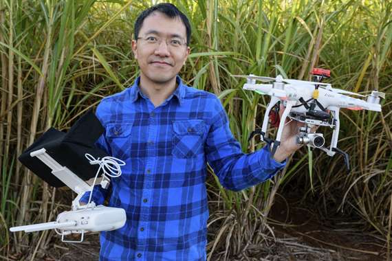Dr Chengyuan (Stephen) Xu holding two drones in a crop field