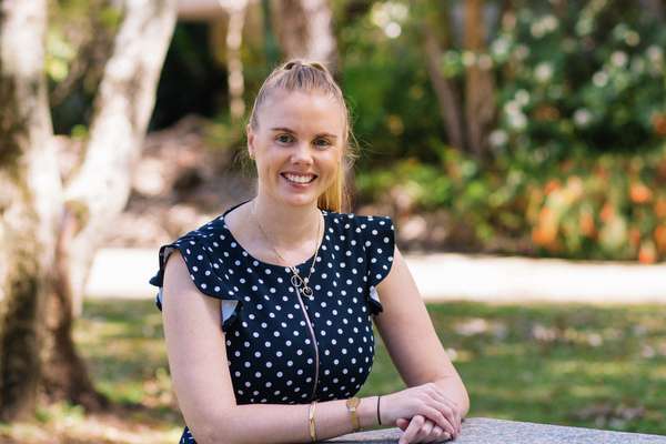 Emily Keehn sitting down smiling and using a laptop down smiling