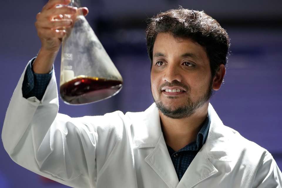 Engineering student with lab coat measuring chemicals.