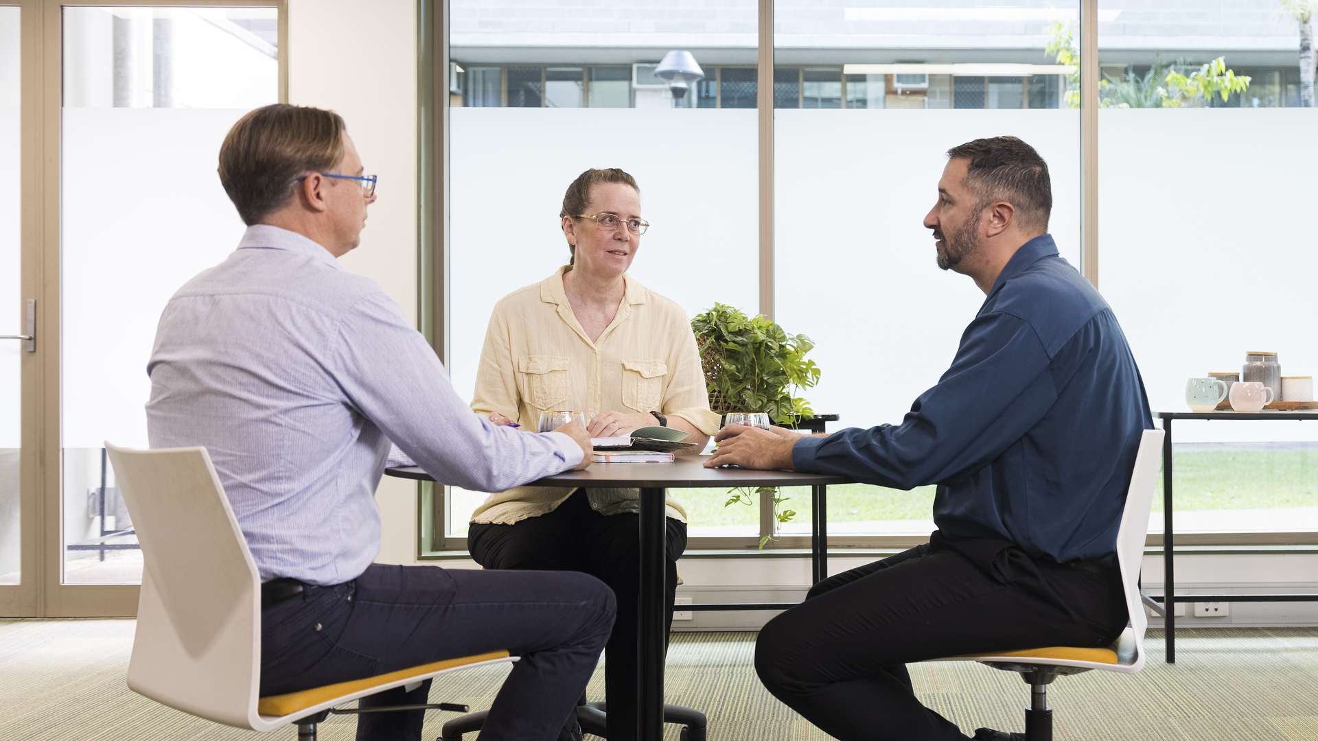 Three people sitting together and talking at a table