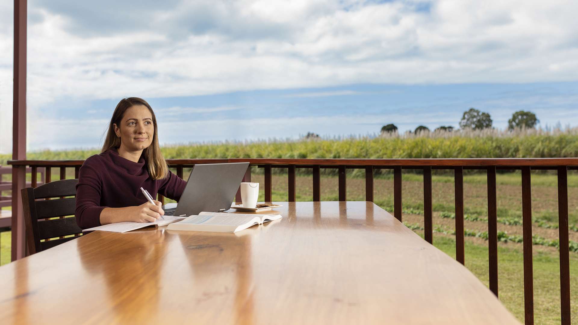 CQU student sitting at a table on her veranda, using her laptop