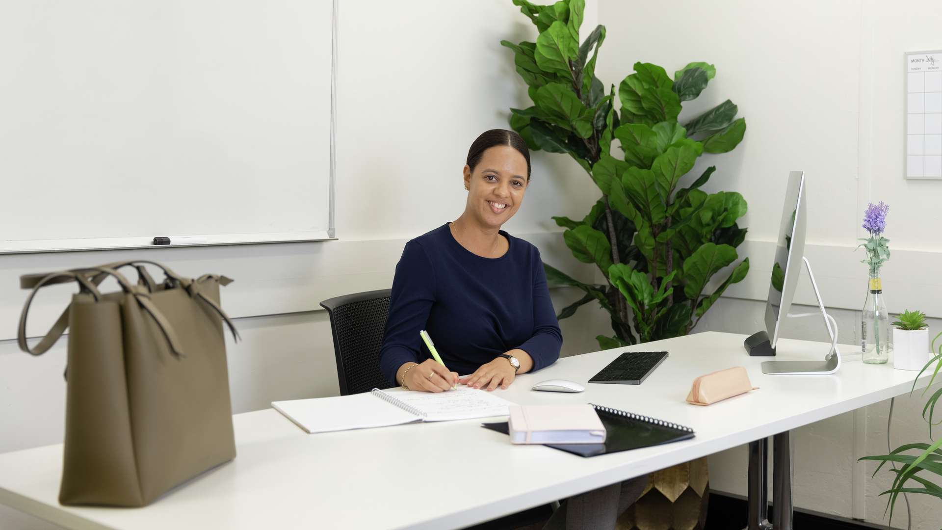 A postgraduate student taking notes at a desk in an office