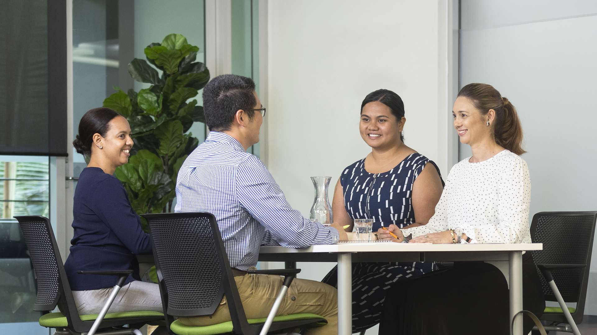 Four business students sitting at a table discussing with one another.