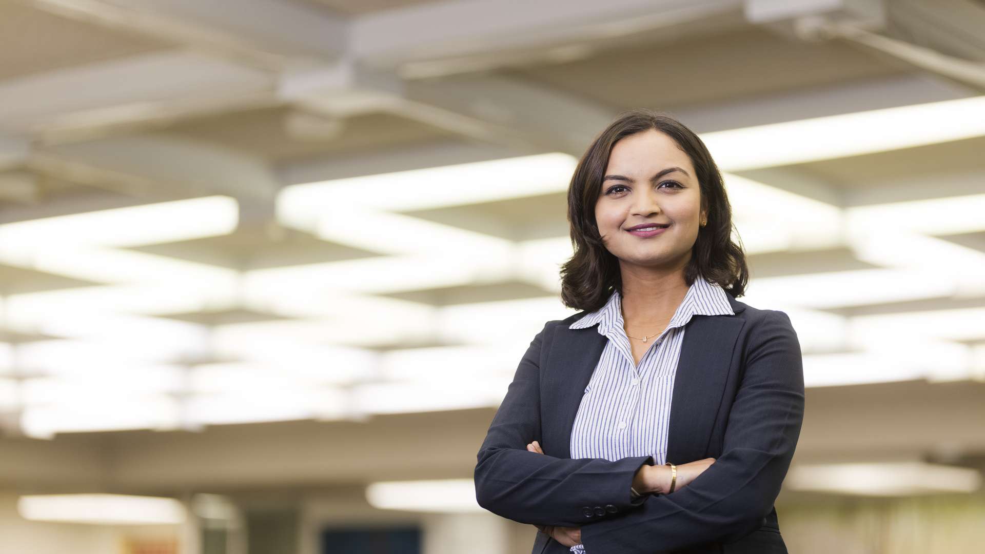 Richa Neupane, a business student standing smiling at the camera with their arms crossed.