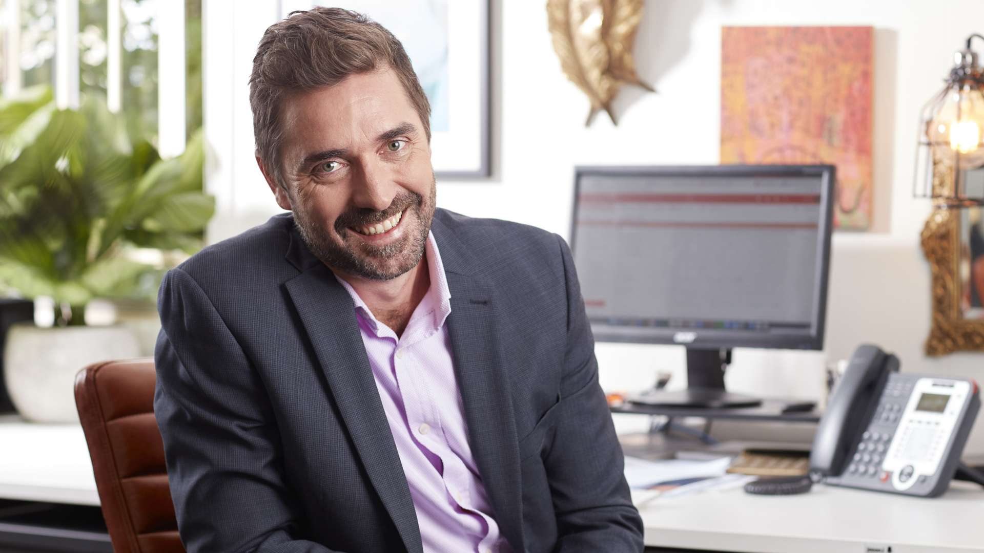 Man turned around smiling, on a desk chair