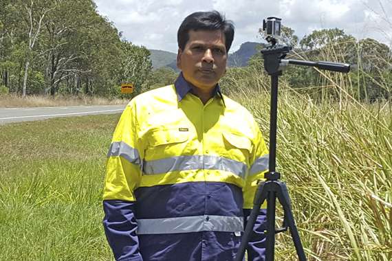 Professor Brijesh Verma standing on the side of the road with a camera on a tripod
