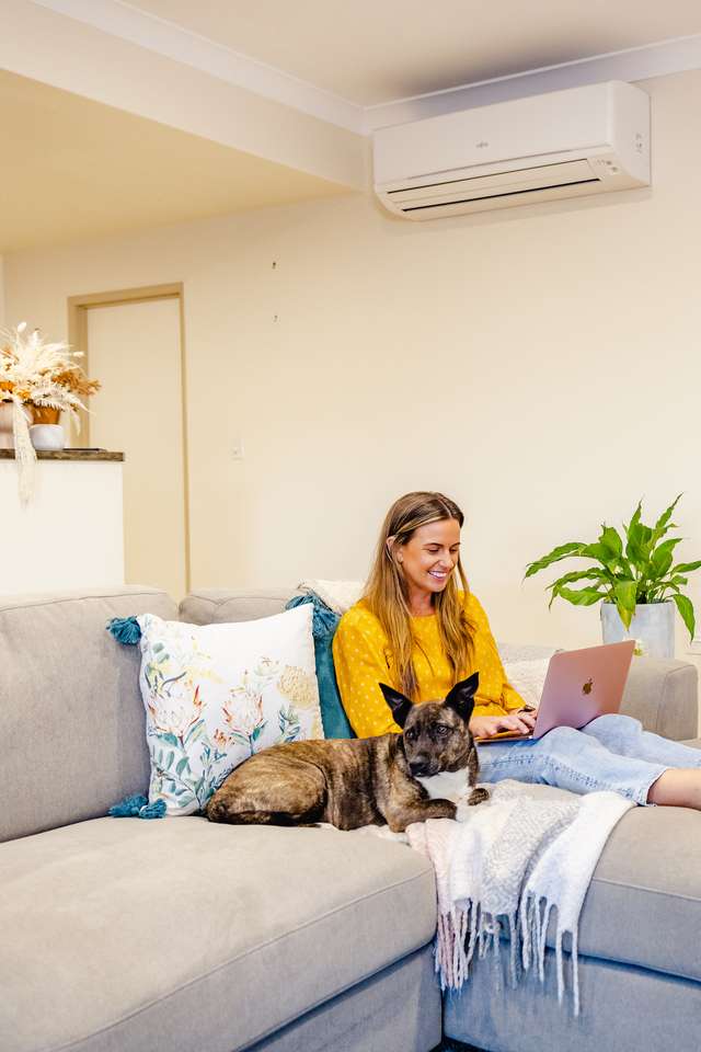 a student studying on the couch with their dog at home