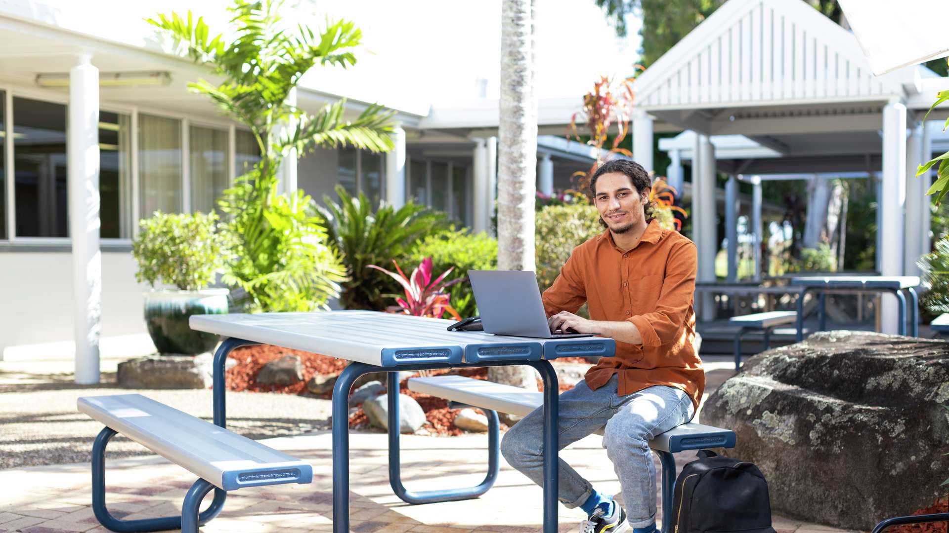A First Nations student studying outside using a laptop