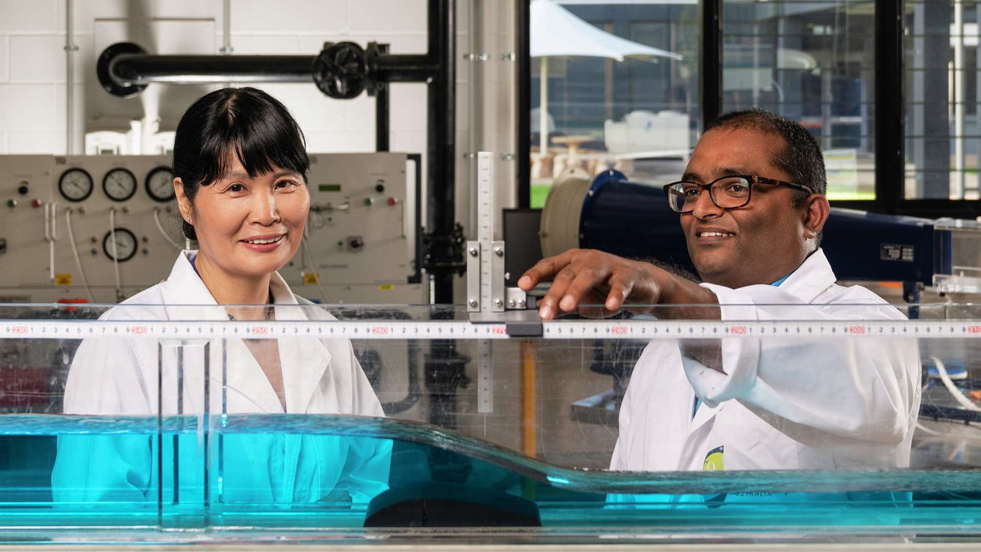 Two CQUni researchers wearing lab coats as they measure water displacement