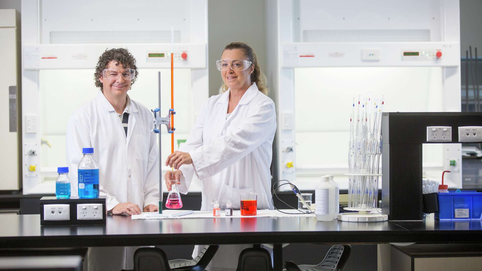 Two science students in white coats experimenting in a lab