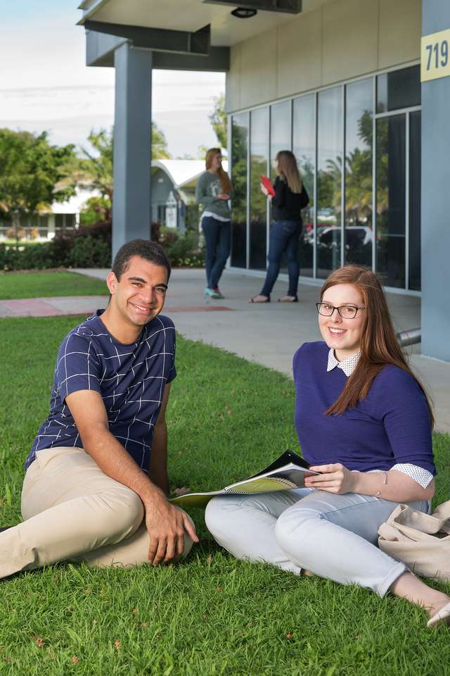 Two students sitting and studying on the grass outside Mackay campus library
