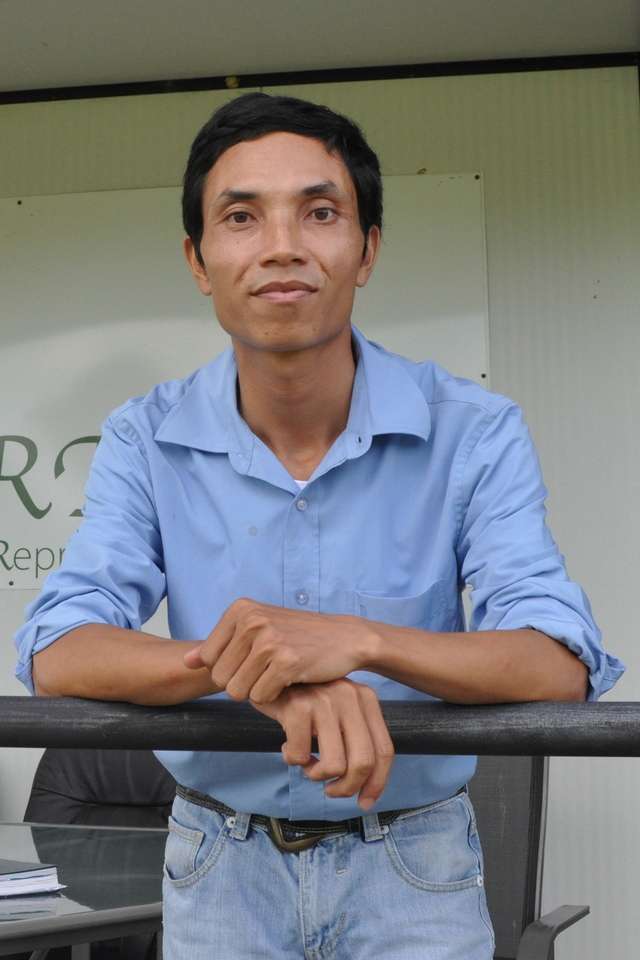Vietnamese student, Do Van Huong standing on a veranda with a white sign, with green decals behind him