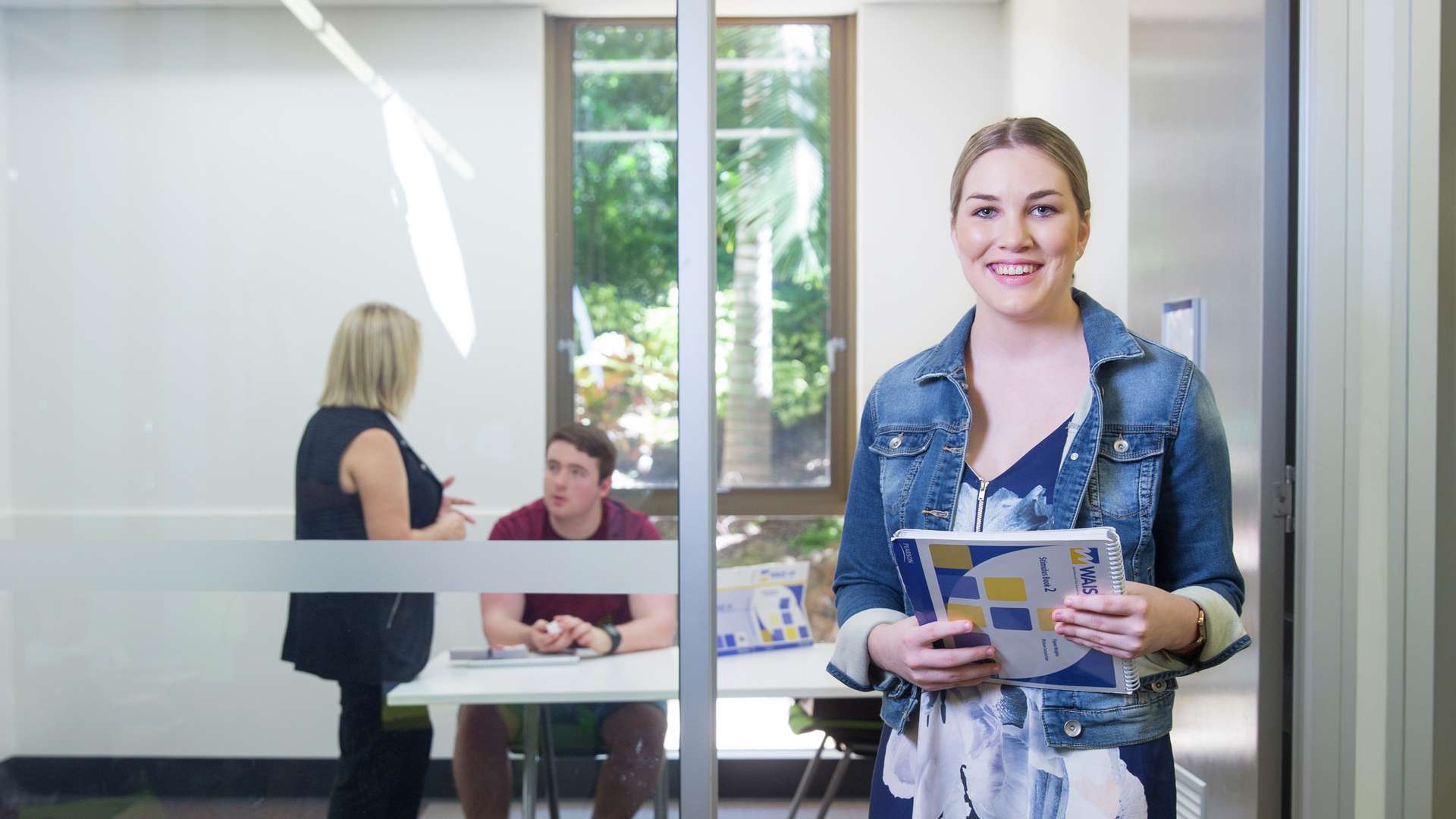 A psychology student holding a textbook in front of a tutorial room