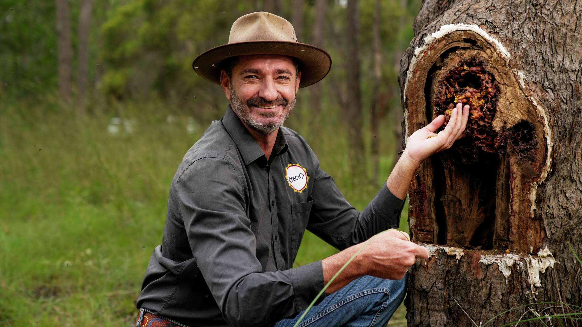 A tutor showing the Bundaberg bee scene in trees whilst looking at camera.