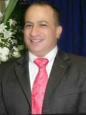 Abdul Tawara smiling wearing a suit with a red tie