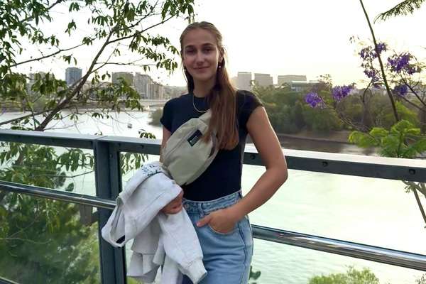 International CQUGlobal student Alea Laetita Wolf from Germany standing outdoors with hand in pocket holding a jumper and smiling at camera.