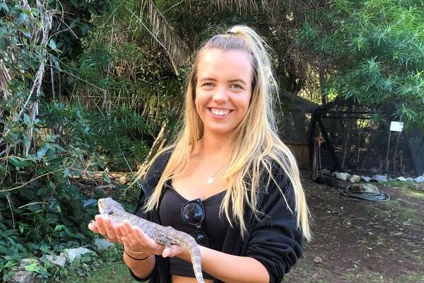 Alice Reeves holding a bearded dragon at a wildlife sanctuary