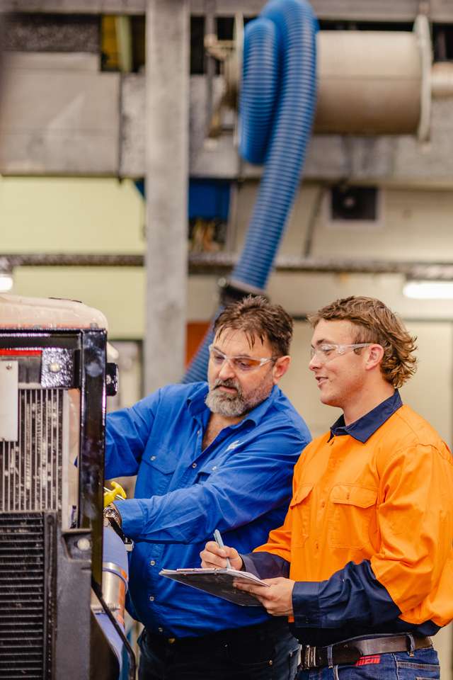 Apprentice working on machinery with a teacher