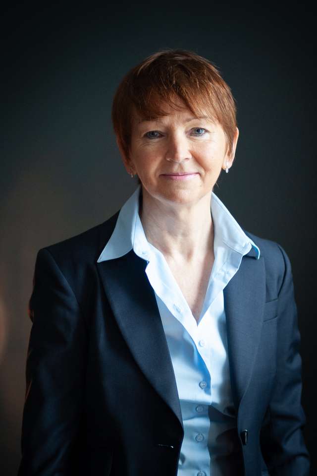 Sheila Doyle smiling wearing light blue business shirt and navy suit coat