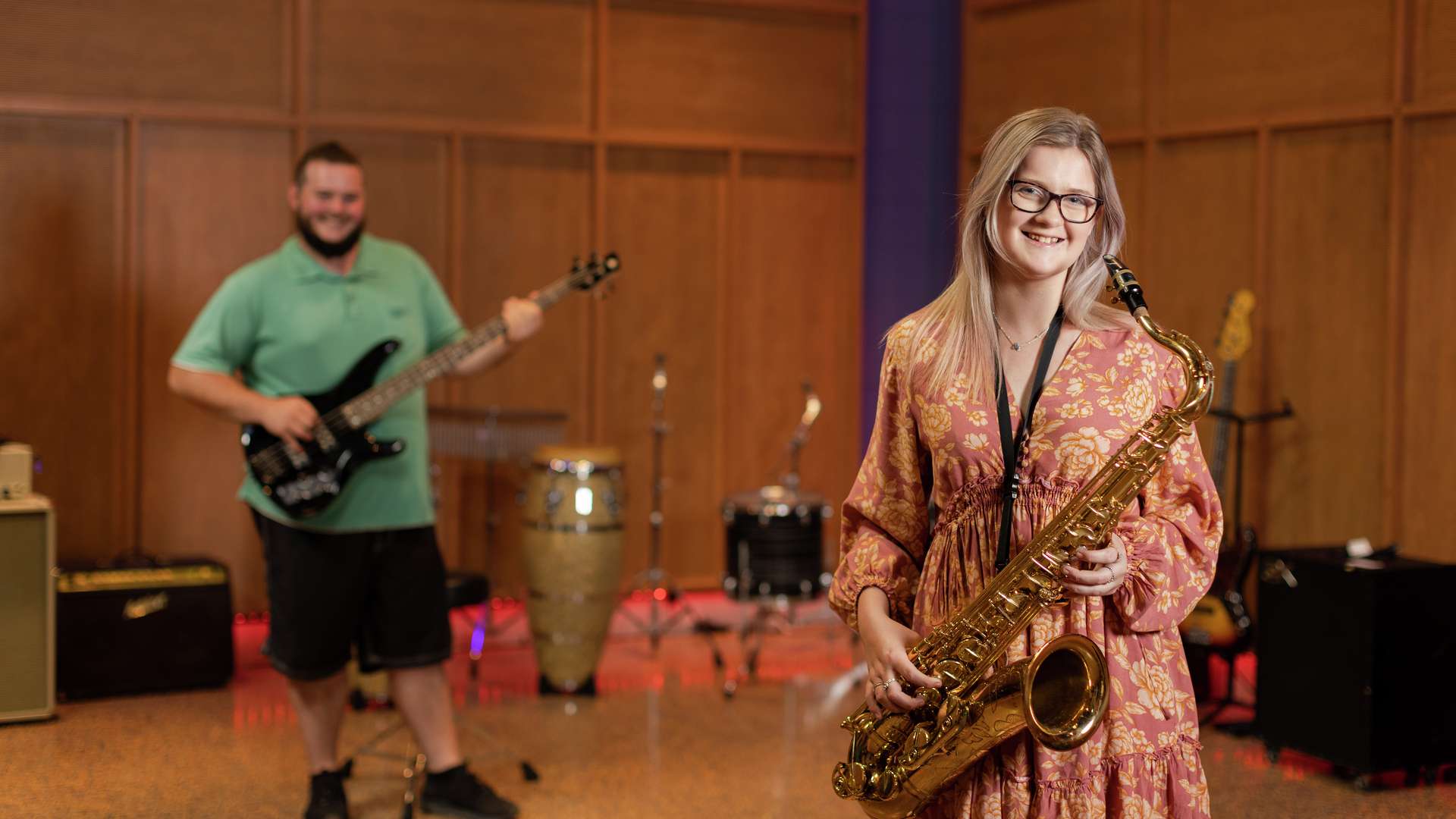 Two music students in a studio with a saxophone and guitar