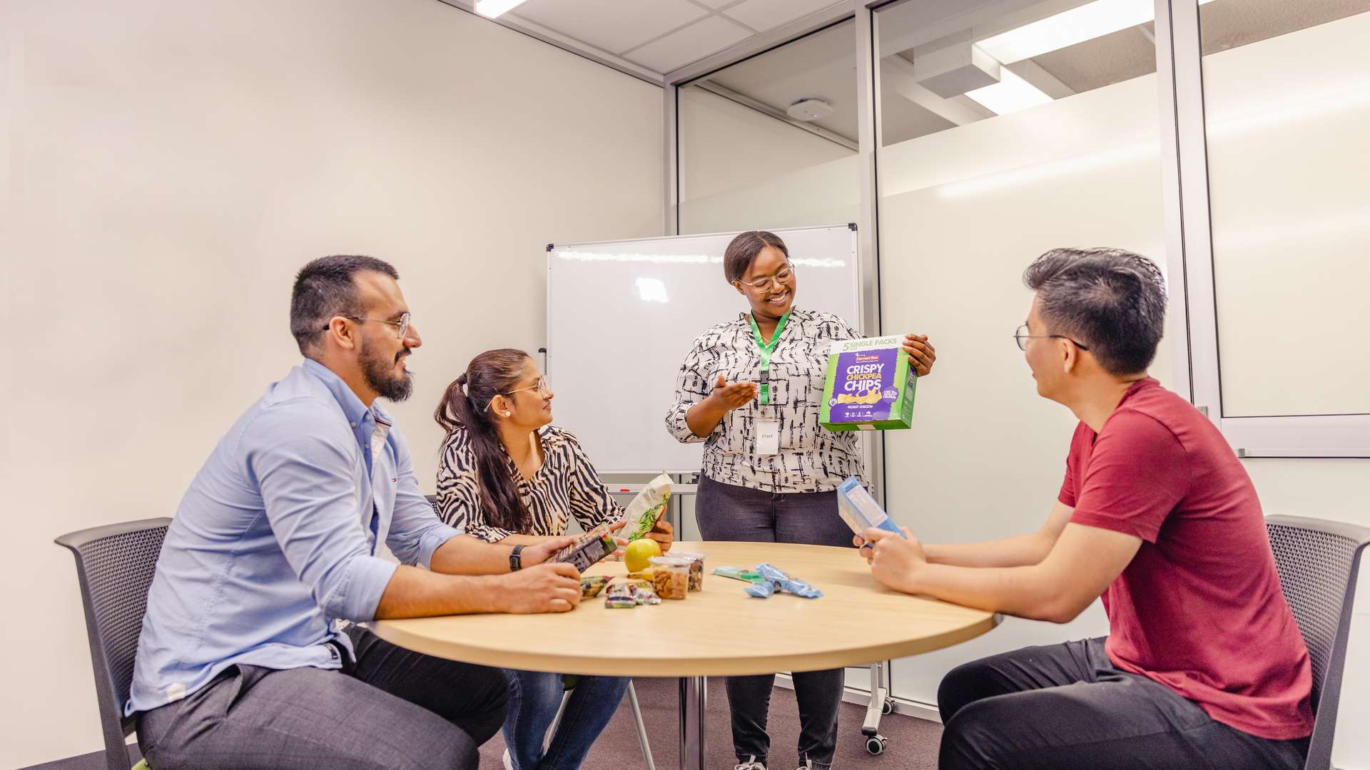 A group of nutrition students sitting at round table with teacher talking about a box of food.